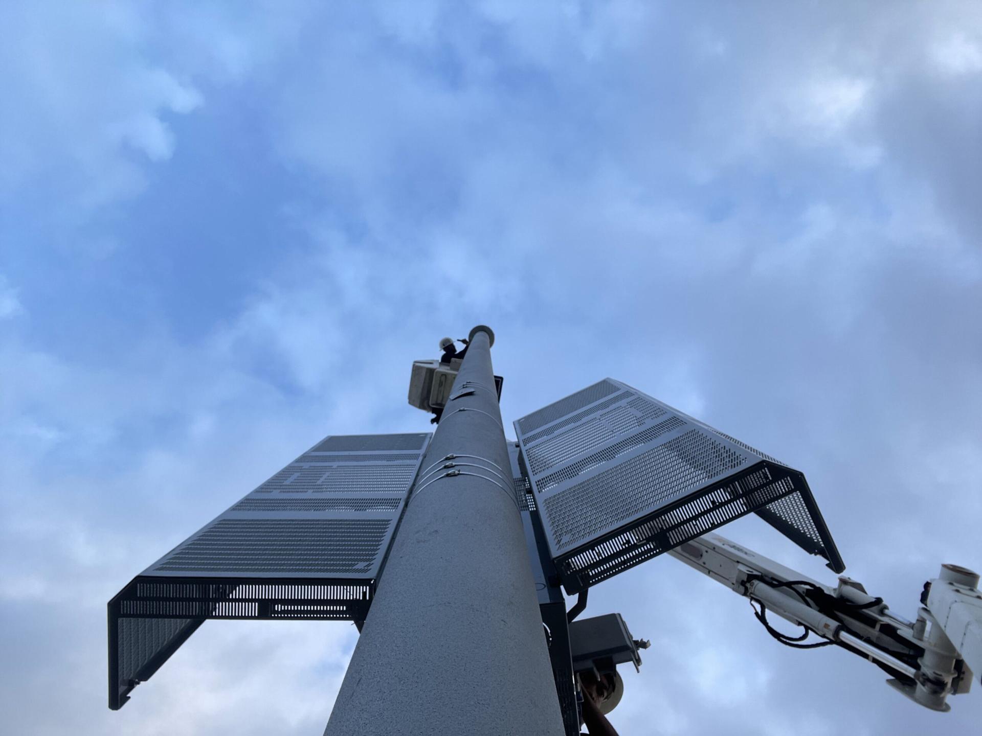 A technician in a bucket lift working at the top of an EasyStreet composite pole fitted with small cell equipment shrouds.
